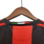 Camisa titular AC Milan 10/11 Adidas: vermelho e preto, com detalhes em dourado pela camisa. Dentro da gola, bandeira da Itália e escrito AC MILAN. Na nuca, bandeira italiana. Logo Adidas e escudo Milan bordados.