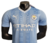 camisa- manchester city- home- 1- azul claro- branca- jogador- masculina- puma- 23/24- escudo- emborrachado- etlhad eiways- gola- v-3 png