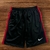 Shorts masculinos Nike Dry-Fit com detalhes em vermelho e logo bordado na parte inferior.