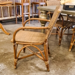 Cadeira de madeira e fibra natural com apoio de braço, refletindo o estilo descontraído de Bali/Asia, disponível na Marcenaria Tiradentes.