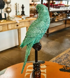 Pássaro decorativo feito de resina verde, posicionado sobre um elegante pedestal de madeira, exemplificando artesanato sofisticado e sustentável da Marcenaria Tiradentes.