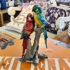 Dupla de pássaros decorativos em resina nas cores vermelho, azul e amarelo, ideal para decoração sustentável e sofisticada.