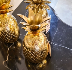 Pote decorativo em formato de abacaxi, feito de metal dourado, ideal para decoração de ambientes internos e externos.