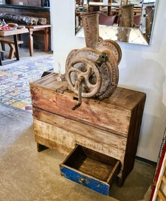 Debulhador de milho vintage sobre aparador de madeira de demolição, ideal para decoração diferenciada em ambientes internos.