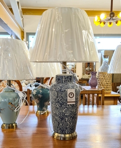 Abajur decorativo em cerâmica branca e azul com detalhes em metal, ideal para iluminação de ambientes sofisticados.