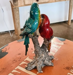 Dupla de pássaros decorativos em resina nas cores vermelho, azul e amarelo, ideal para decoração sustentável e sofisticada.