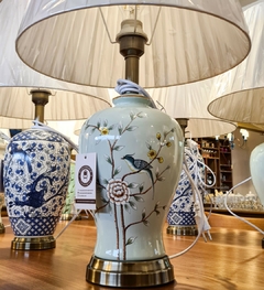 Abajur artesanal em cerâmica azul claro decorado com pássaros verdes e cúpula, ideal para iluminação e decoração sofisticada.