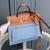 Bolsa Hermès Herbag Zip 31 Canvas Azul Claro/Marrom: Uma bolsa de lona com detalhes em azul claro e marrom, ideal para um visual elegante e casual ao mesmo tempo.