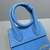 Bolsa Jacquemus Le Chiquito Noeud Suede Blue: Uma pequena bolsa transversal de camurça azul da marca de moda Jacquemus, com um laço decorativo, adicionando um toque de elegância ao seu visual.