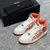 Tênis Amiri Skel Top Hi "White/Orange": Calçado alto em branco com detalhes em laranja, design moderno da marca Amiri.