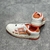 Amiri Skel Top Low "White/Orange" Sneakers: White low shoes with orange details, modern design from the Amiri brand.