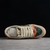 Gucci Screener GG Beige/Green Sneakers: A pair of sneakers with green accents on a beige background, evoking a modern urban style with a retro vibe.