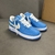 Tênis Louis Vuitton x Nike Air Force 1 Low By Virgil Abloh Light Blue: Um par de tênis na cor azul claro, parte da colaboração entre Louis Vuitton e Nike, desenhado por Virgil Abloh.