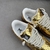 Tênis Louis Vuitton x Nike Air Force 1 Low By Virgil Abloh Metallic Gold: Um par de tênis em dourado metálico, parte da colaboração entre Louis Vuitton e Nike, projetado por Virgil Abloh.