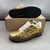 Tênis Louis Vuitton x Nike Air Force 1 Low By Virgil Abloh Metallic Gold: Um par de tênis em dourado metálico, parte da colaboração entre Louis Vuitton e Nike, projetado por Virgil Abloh.