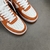 Louis Vuitton x Nike Air Force 1 Low By Virgil Abloh Orange/White Sneakers: A pair of orange and white sneakers, the result of a collaboration between Louis Vuitton and Nike with an exclusive design by Virgil Abloh.