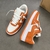 Tênis Louis Vuitton x Nike Air Force 1 Low By Virgil Abloh Orange/White: Um par de tênis em laranja e branco, resultado da colaboração entre Louis Vuitton e Nike com design exclusivo de Virgil Abloh.