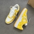 Louis Vuitton x Nike Air Force 1 Low By Virgil Abloh Yellow/White Sneakers: A pair of yellow and white sneakers, the result of a collaboration between Louis Vuitton and Nike with an exclusive design by Virgil Abloh.