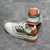 Tênis LV Trainer Branco/Verde/Laranja: Um tênis de estilo esportivo, com detalhes em verde e laranja, perfeito para um visual urbano e moderno.