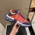 Versace Trigreca "Orange/Pink/Purple" Sneakers: Vibrant orange, pink and purple sports shoes from Versace's Trigreca line, featuring the iconic Medusa logo and high-quality details.