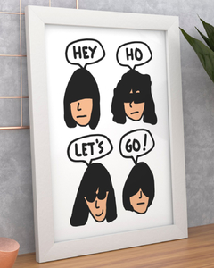 quadro com desenho do rosto dos integrantes da banda Ramones dizendo "hey ho let's go!", em tamanho A4, com moldura branca.