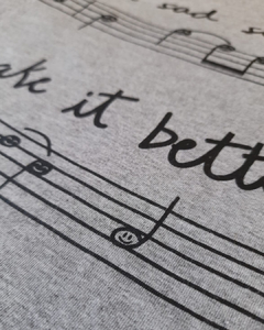 camiseta cinza com desenho de uma partitura e notas musicais com carinhas, e a frase "take a sad song and make it better", em tamanho infantil, sem gênero