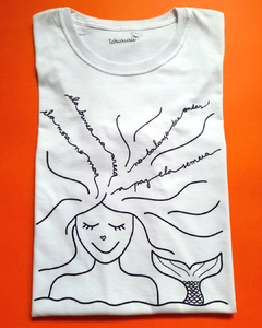 camiseta branca com desenho de uma sereia, com a frase "ela mora no mar, ela brinca na areia, no balanço das ondas a paz ela semeia", em tamanho infantil, sem gênero