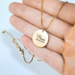 Colar personalizado em ouro 18k com nome e data gravados, segurado na mão.