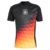 Germany 24/25 Pre-Match Jersey: Front view. Black design with yellow, orange, and red diamonds. Central DFB crest and Adidas logos on the sleeves. Unique style for Euro 2024.