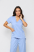 Uma modelo vestida de scrub feminino azul claro celeste , que esta à venda, composto por uma blusa de manga curta e uma calça na cor azul claro celeste. A blusa possui um decote em V, dois bolsos frontais e mangas curtas. o scrub é lindo.