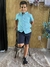 Garoto usando um conjunto infantil masculino da marca Trick Nick, com camisa azul e bermuda escura, posando em uma cadeira. VALENTINA MODA