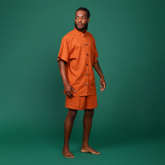 Imagem de modelo com manequim 38, altura de 1,75 e peso de 61 kg, usando o tamanho M de uma camisa oversized em linho na cor terracota. A peça apresenta bolso lateral, botões de casca de coco