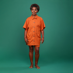 Imagem de modelo com manequim 38, altura de 1,55 e peso de 52 kg, usando o tamanho P de uma camisa oversized em linho na cor terracota. A peça apresenta bolso lateral, botões de casca de coco