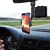 Suporte universal para celular 360° montado no painel de um carro, segurando um smartphone com uma imagem de paisagem.