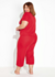 Pijama em helanca de poliéster vermelho com decote V e amarração decorativa, modelagem plus size, visto de costas por uma modelo.