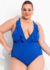 Mulher plus size usando um maiô azul com detalhes em babados, posando com confiança.