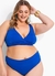 Modelo plus size usando biquíni azul com detalhes em drapeado, sorrindo e posando com confiança.