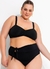 Modelo plus size usando biquíni preto com parte de cima com detalhes franzidos e parte de baixo alta com laço na lateral.