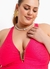 Modelo plus size usando maiô pink com detalhe em V e acessórios de pérola e flor dourada