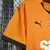 Imagem da camisa titular do Galatasaray 2024/2025 Puma com design meio a meio em laranja e amarelo, detalhes em preto e logo da Puma em vermelho.