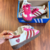 Tênis Adidas Samba X CDG na cor rosa e branca, com detalhes em vermelho e estampa de corações.