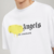 TSHIRT PALM ANGELS LOS ANGELES SPRAYED Camiseta branca Palm Angels com estampa em spray amarelo e texto "Los Angeles".