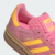 Tênis Adidas Gazelle Indoor Bold na cor rosa com detalhes em amarelo e solado transparente.