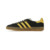 Tênis ADIDAS GAZELLE INDOOR na cor preto com detalhes em amarelo, modelo com três listras laterais e sola translúcida.