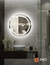 Round LED mirror with a luminous glass halo in a modern bathroom setting.