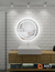 Round LED mirror with luminous halo glow, displayed in a modern bathroom setting with a white tiled wall and wooden vanity.