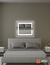 Espejo LED rectangular Glanz Luminous Glass de 60 x 52 cm sobre la pared en un dormitorio moderno, con un diseño minimalista y elegante.