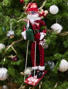 Muñeco de Santa Claus esquiador con trineo, vestido de rojo, decorando un árbol de Navidad.