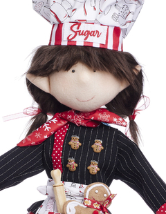 Doll Duenda Chef con gorra blanca y roja, delantal negro y decoraciones navideñas, sosteniendo un rodillo y una galleta de jengibre.