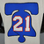 Camiseta regata branca do Philadelphia 76ers, com a imagem de um sino e o número 21 em destaque.